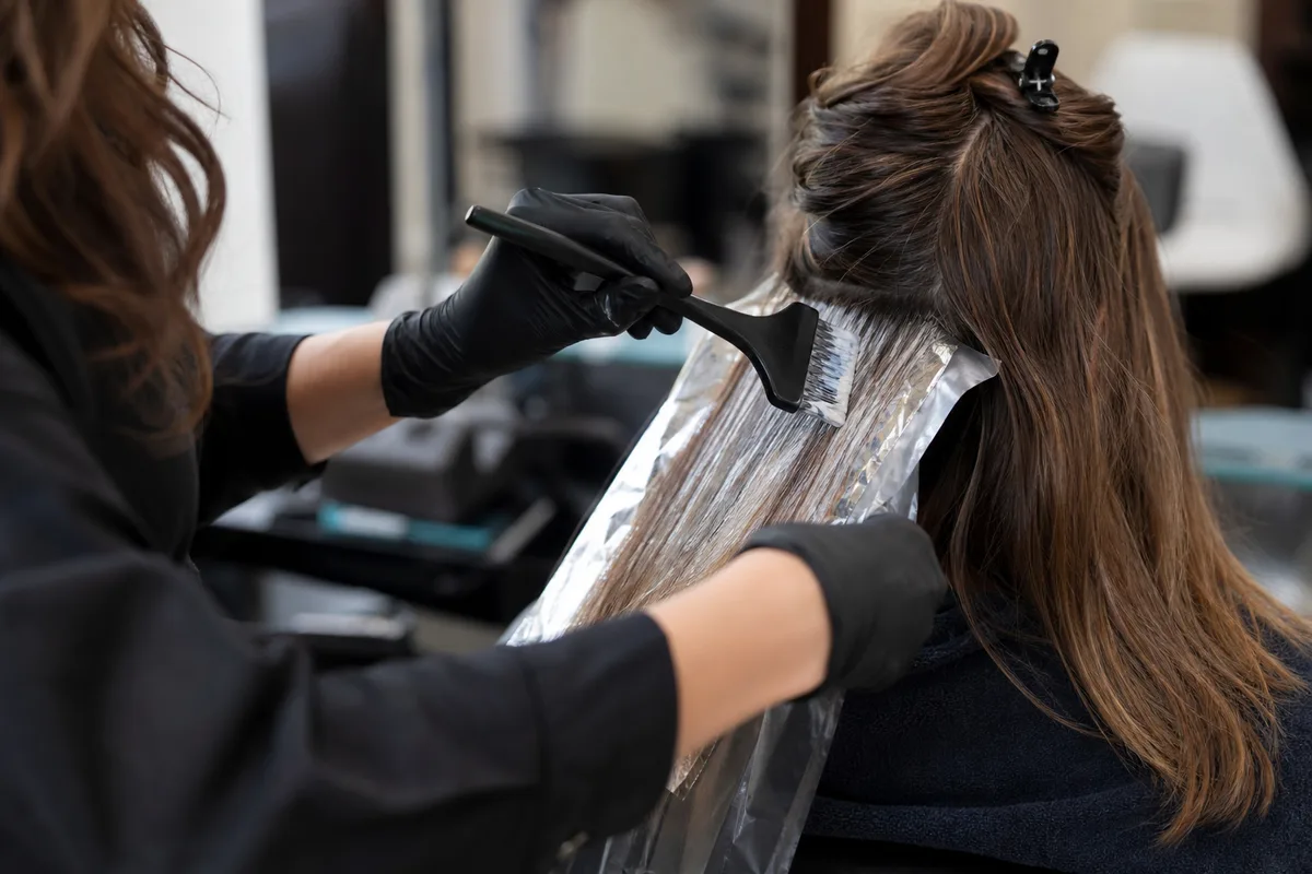 Coiffeuse réalisant une coloration sur une cliente dans un salon moderne